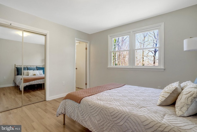 bedroom with baseboards, a closet, and light wood finished floors