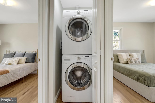 washroom featuring laundry area, stacked washing maching and dryer, and light wood-type flooring