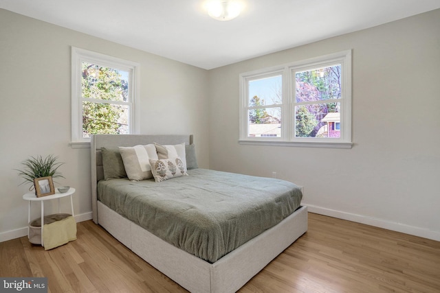 bedroom featuring light wood-style flooring, multiple windows, and baseboards