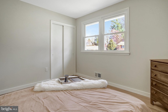 bedroom with baseboards, visible vents, and a closet