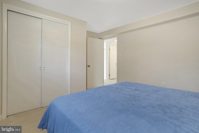 bedroom featuring light colored carpet and a closet