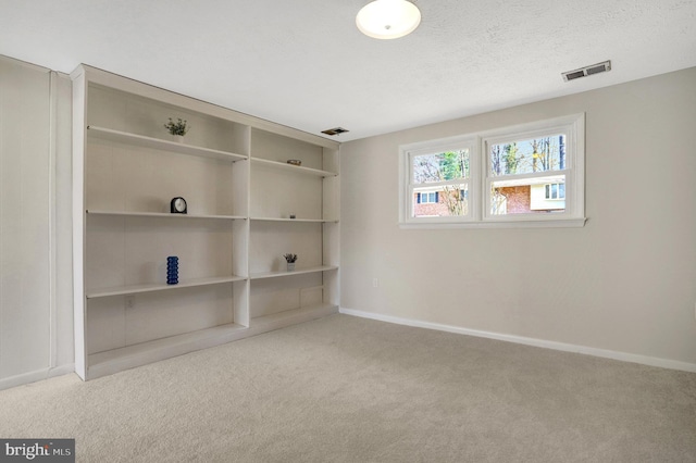 carpeted empty room featuring visible vents, baseboards, and a textured ceiling