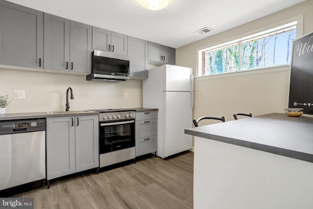 kitchen with visible vents, stainless steel appliances, light wood-type flooring, and a sink