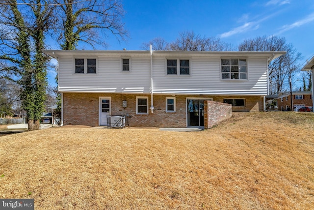 rear view of property featuring a yard and brick siding