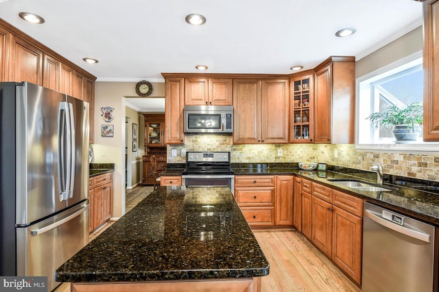 kitchen with ornamental molding, light wood-style flooring, a sink, tasteful backsplash, and stainless steel appliances