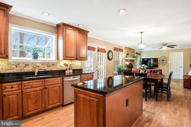 kitchen featuring light wood finished floors, open floor plan, decorative backsplash, stainless steel dishwasher, and a sink