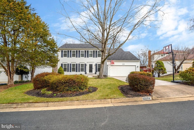 colonial-style house with concrete driveway, a garage, a front yard, and roof with shingles