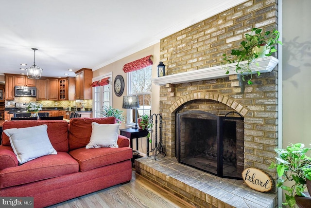 living area with a fireplace, crown molding, and wood finished floors