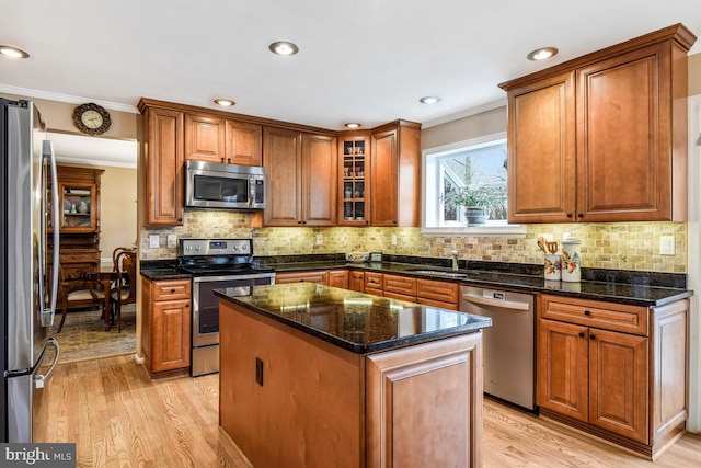 kitchen with brown cabinetry, light wood-style flooring, appliances with stainless steel finishes, and a kitchen island