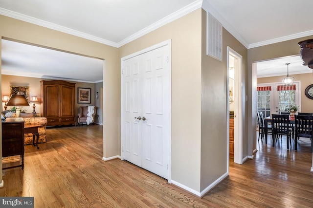 hallway featuring baseboards, wood finished floors, and crown molding