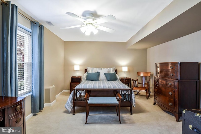 bedroom with visible vents, light colored carpet, baseboards, and ceiling fan