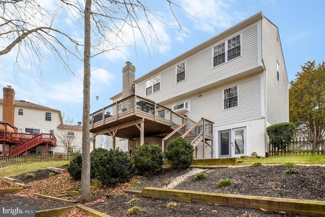 back of house featuring stairway, a chimney, a deck, and fence