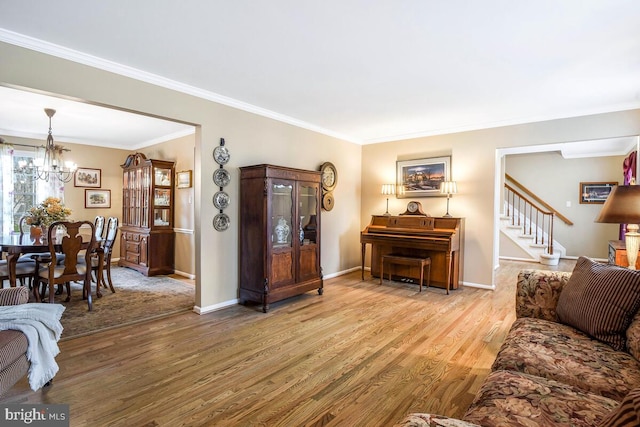 living room with ornamental molding, wood finished floors, baseboards, a chandelier, and stairs