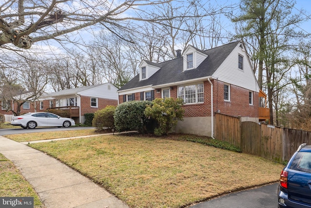 view of front of house with brick siding, a front yard, and fence