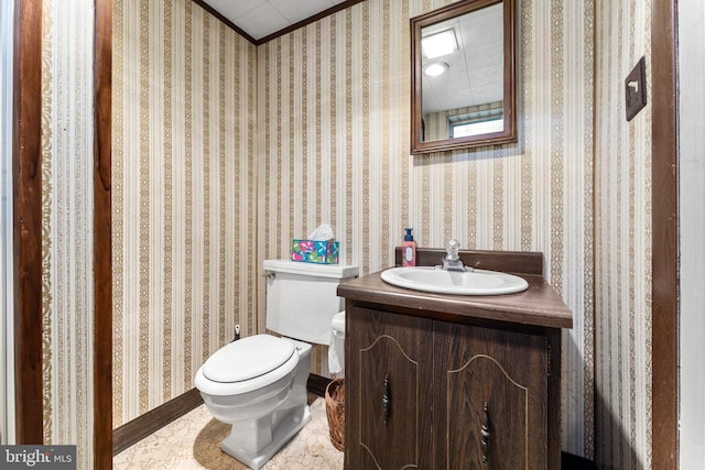 half bath with toilet, vanity, and wallpapered walls