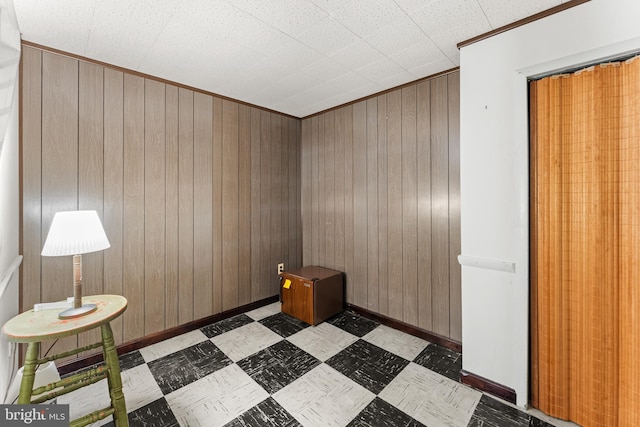 interior space with tile patterned floors, baseboards, and wood walls