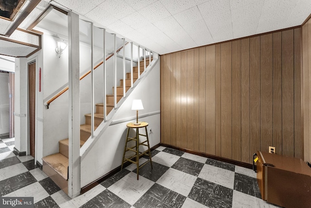 stairway with tile patterned floors and wood walls