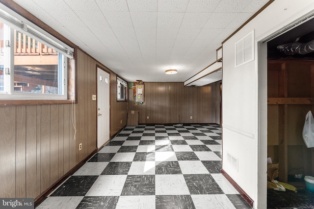 corridor with dark floors, visible vents, and wood walls