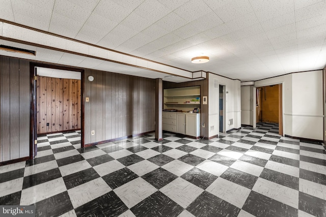 unfurnished room with tile patterned floors, baseboards, and wood walls