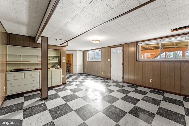 below grade area featuring tile patterned floors, baseboards, and wood walls