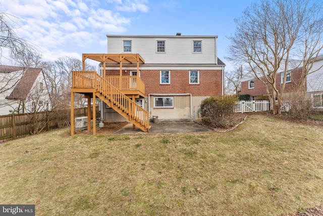 back of house featuring a lawn, a deck, a fenced backyard, brick siding, and stairs