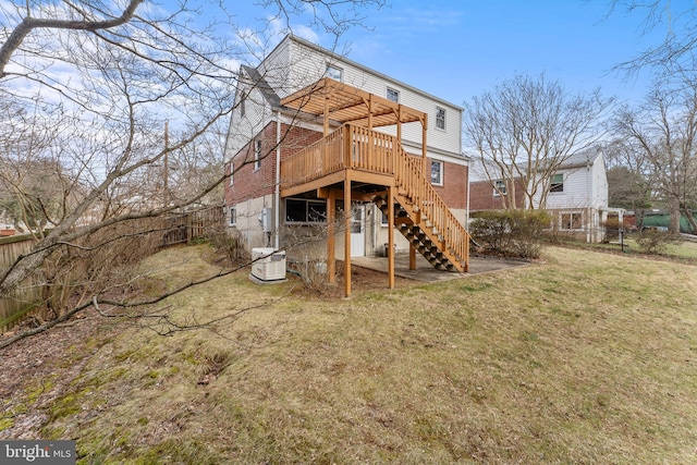 back of house featuring stairway, fence, a deck, a lawn, and brick siding