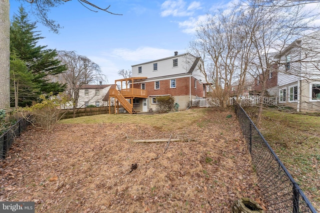 back of property with brick siding, fence private yard, stairs, a lawn, and a deck