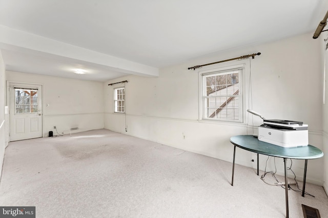 spare room with beamed ceiling, carpet flooring, and visible vents