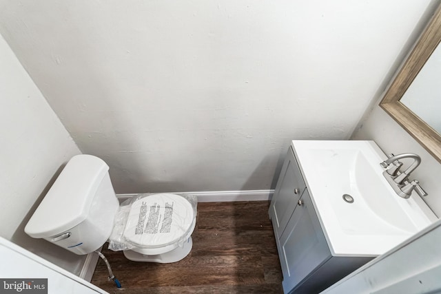bathroom featuring toilet, baseboards, vanity, and wood finished floors