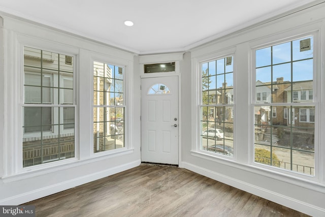 entryway with a wealth of natural light, wood finished floors, baseboards, and ornamental molding