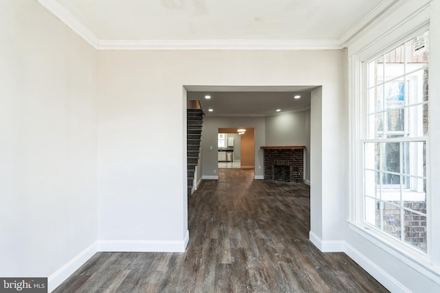 hallway with dark wood-style flooring, ornamental molding, baseboards, and a wealth of natural light