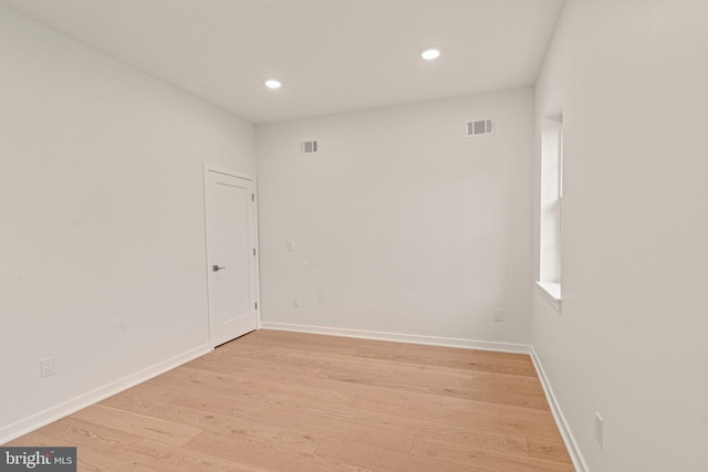 empty room with light wood finished floors, baseboards, and visible vents