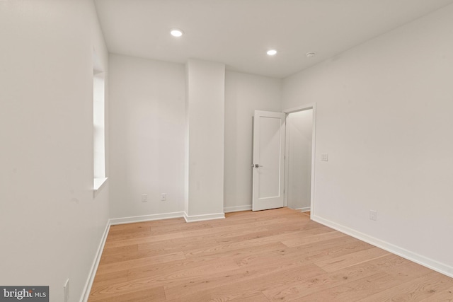 empty room with light wood-type flooring, baseboards, and recessed lighting