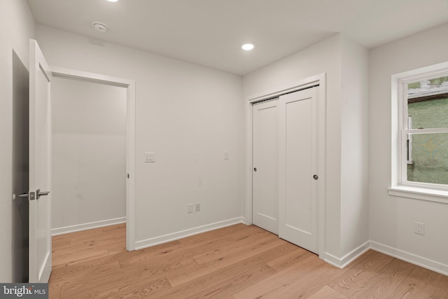 unfurnished bedroom featuring light wood finished floors, baseboards, a closet, and recessed lighting