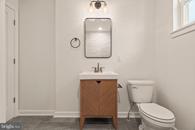 bathroom with toilet, baseboards, and vanity