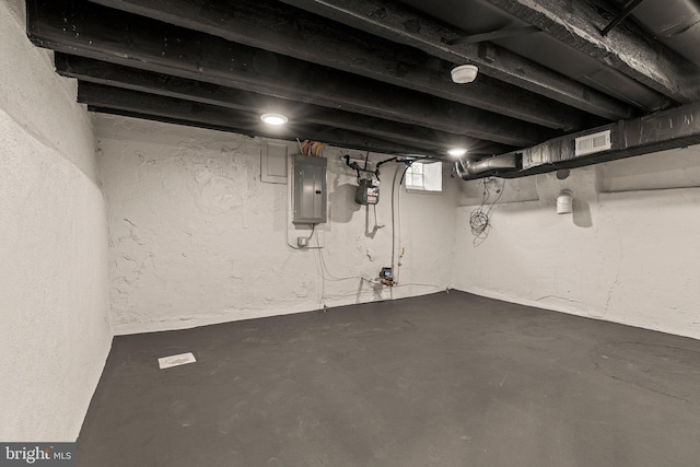 unfinished basement featuring electric panel, visible vents, and a textured wall