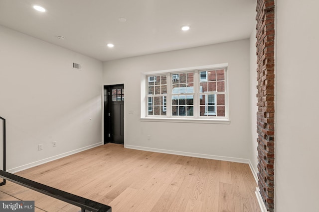 empty room featuring light wood-style floors, baseboards, visible vents, and recessed lighting