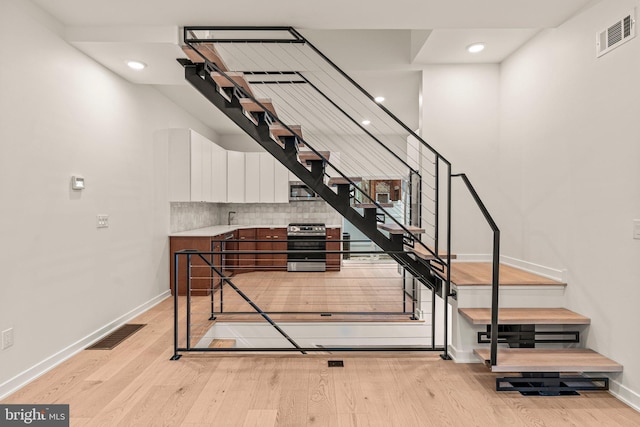 staircase with baseboards, visible vents, wood finished floors, and recessed lighting