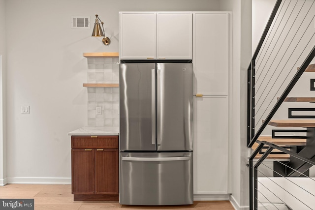 kitchen with visible vents, baseboards, light wood-type flooring, freestanding refrigerator, and open shelves