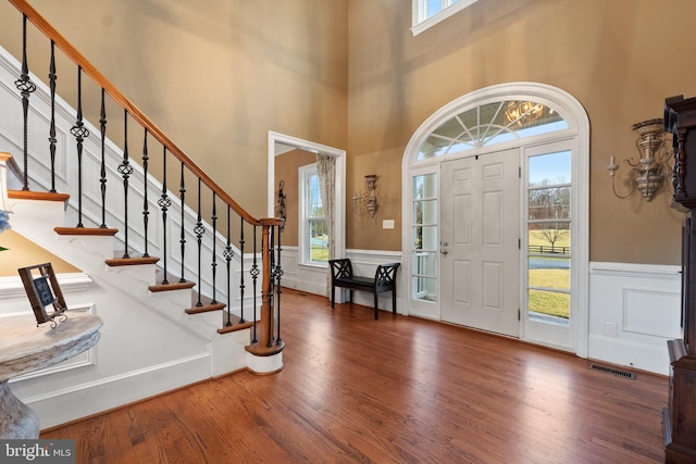 entrance foyer featuring wainscoting, visible vents, plenty of natural light, and wood finished floors