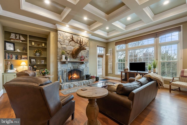 living area with beamed ceiling, a healthy amount of sunlight, wood finished floors, and a fireplace