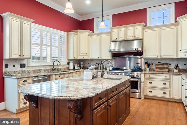 kitchen featuring under cabinet range hood, cream cabinets, and a sink