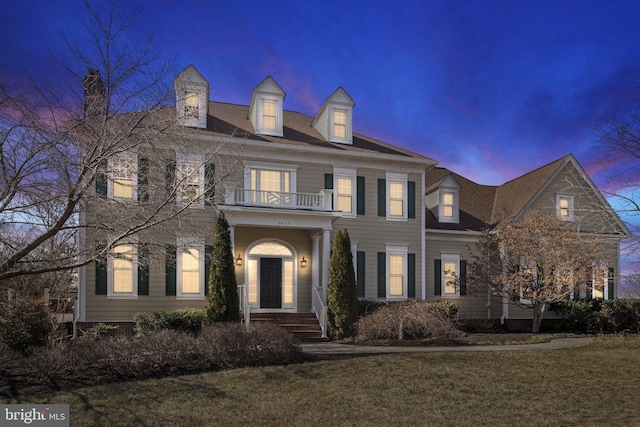 colonial-style house with a balcony and a front yard