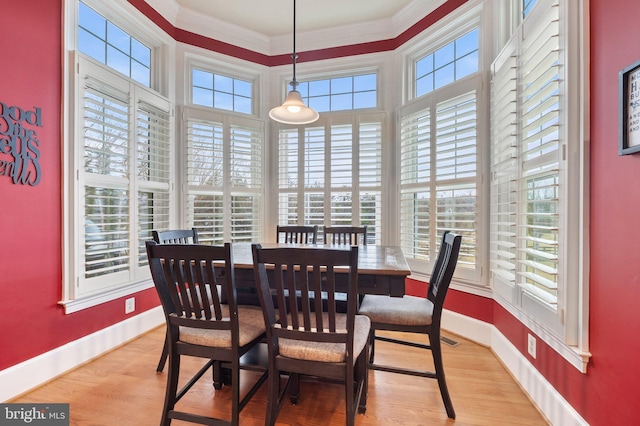 dining room featuring wood finished floors, baseboards, and ornamental molding