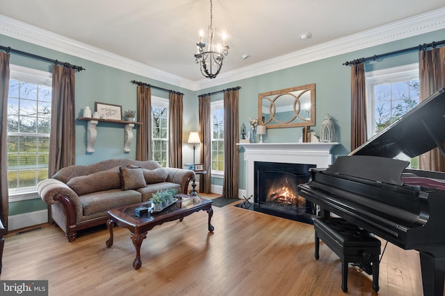 living area featuring visible vents, crown molding, a fireplace with flush hearth, an inviting chandelier, and wood finished floors