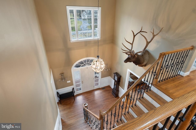 entryway featuring baseboards, stairs, a high ceiling, an inviting chandelier, and wood finished floors