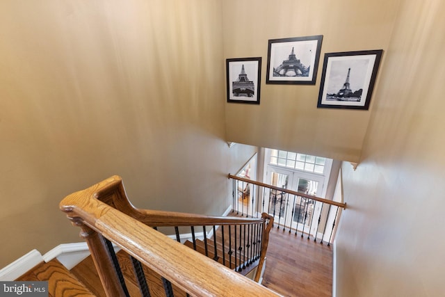 stairs with a high ceiling, baseboards, and wood finished floors