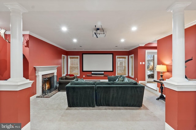 home theater room featuring light carpet, recessed lighting, crown molding, decorative columns, and a brick fireplace