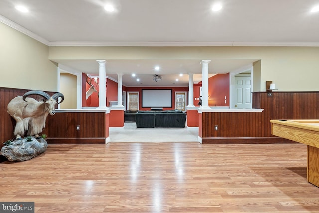 interior space with light wood finished floors, open floor plan, wainscoting, and ornate columns