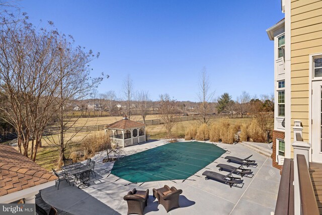 view of swimming pool with a rural view, a patio, fence, and a fenced in pool